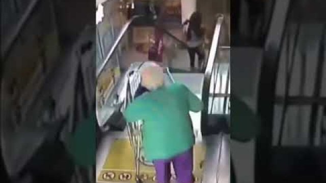 Starsza pani wjeżdża wózkiem na ruchome schody. Spadając robi salto