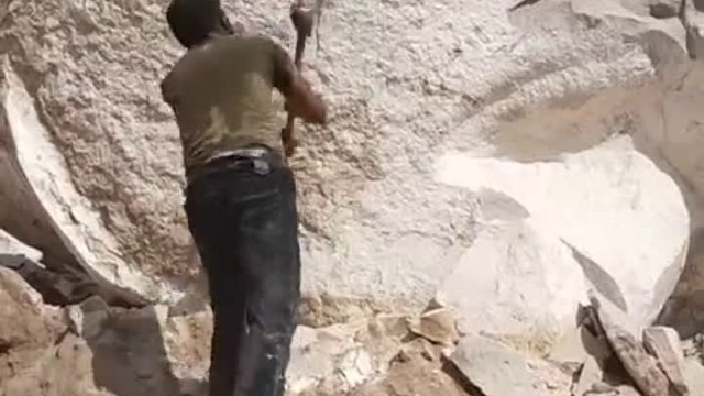 Pracownik rozłupujący kamienie
