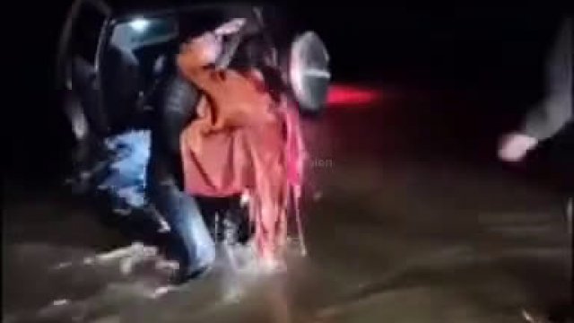 Dżentelmen przenosi kobietę przez powódź