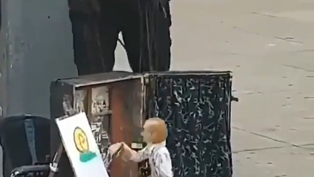 Facet na ulicy maluje obraz za pomocą marionetki