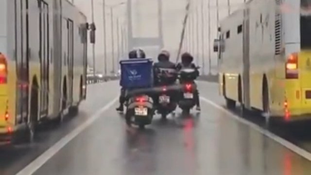 Autobusy pomagają motocyklistom, którzy mają trudności z przejazdem przez most z powodu burzy