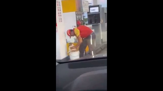 Pracownik stacji benzynowej próbuje ochłodzić bezpańskiego psa podczas fali upałów
