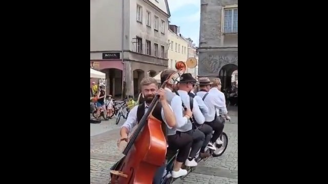 Muzycy grają koncert jadąc przez miasto na sześcioosobowym rowerze