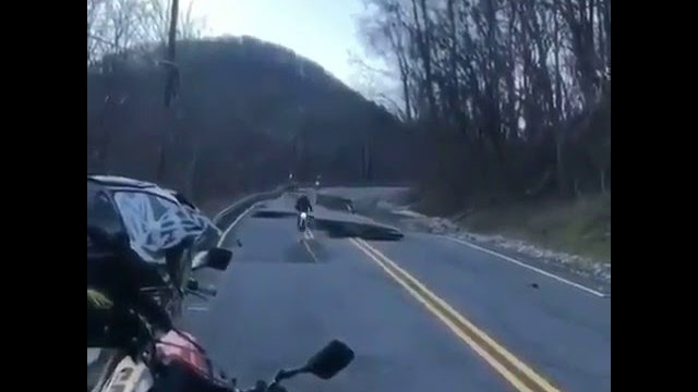 Motocyklista pokonuje zapadniętą drogę