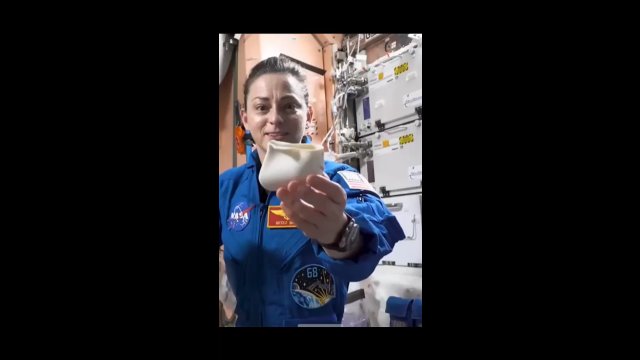 Astronautka pokazuje specjalny kosmiczny kubek, który naśladuje efekt grawitacji