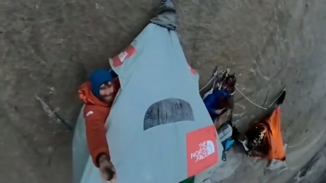 Wspinacze śpią zawieszeni na skalnej ścianie