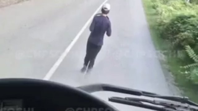 Rusek z kierownicą w ręce biega po ulicy udając samochód