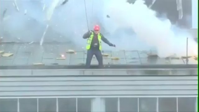 Wyburzanie wieżowce, podczas gdy człowiek stoi na dachu