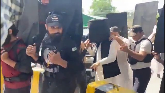 Pracownicy ochrony używają kuloodpornych tarcz, aby zabezpieczyć byłego premiera Pakistanu
