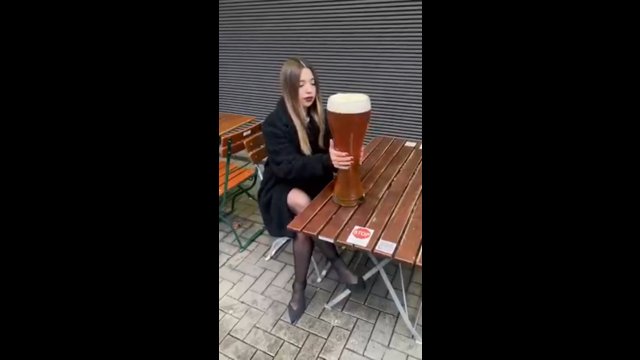 Dziewczyna próbuje wypić ogromną szklankę piwa