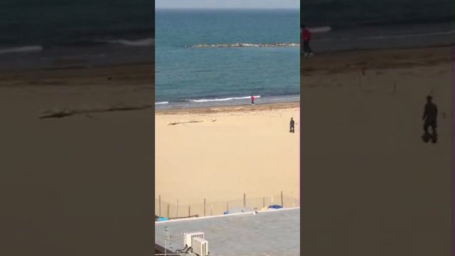 Koleś biegający po plaży ucieka przed policjantem by uniknąć mandatu.