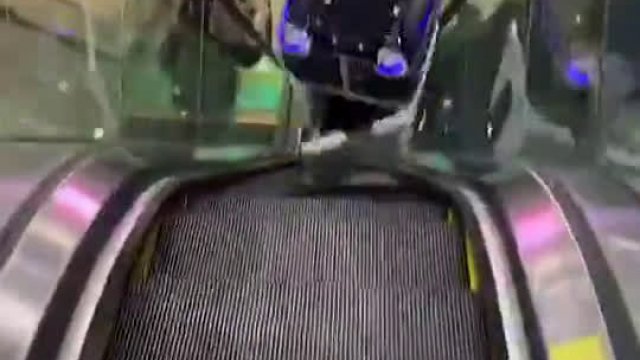 Robot atakuje mężczyznę i kobietę u stóp schodów ruchomych